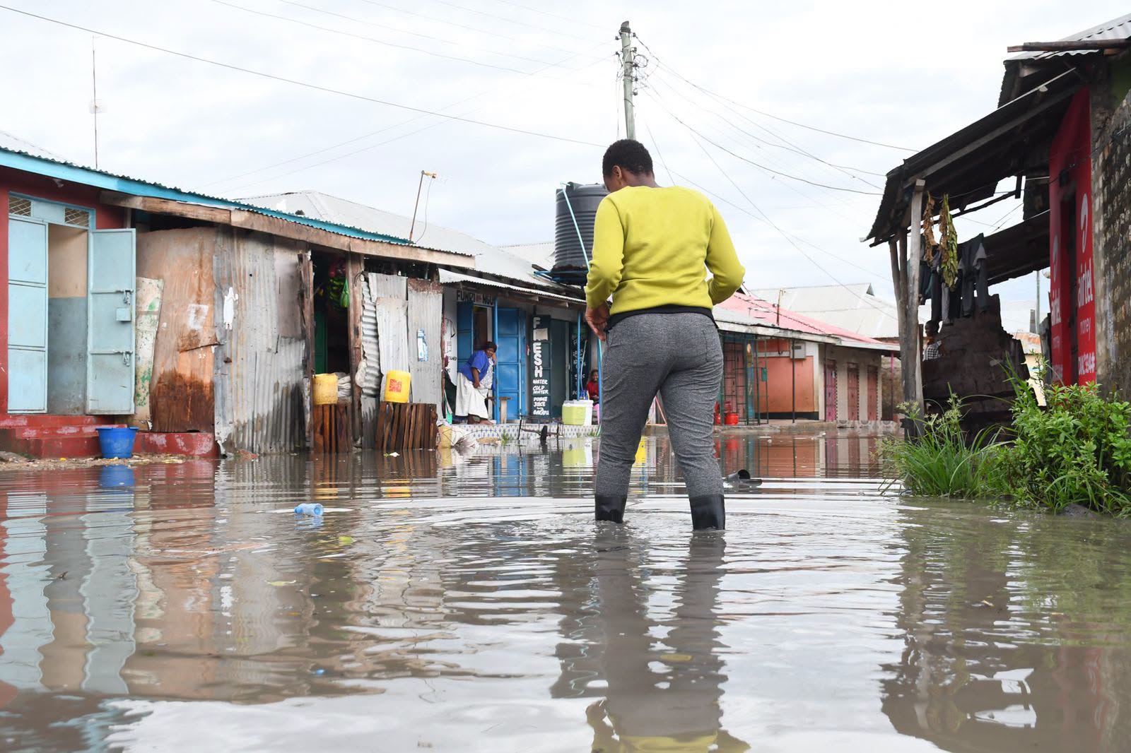 Mombasa flooding 2026 — resident wades through deep floodwater on a submerged street in a residential neighbourhood