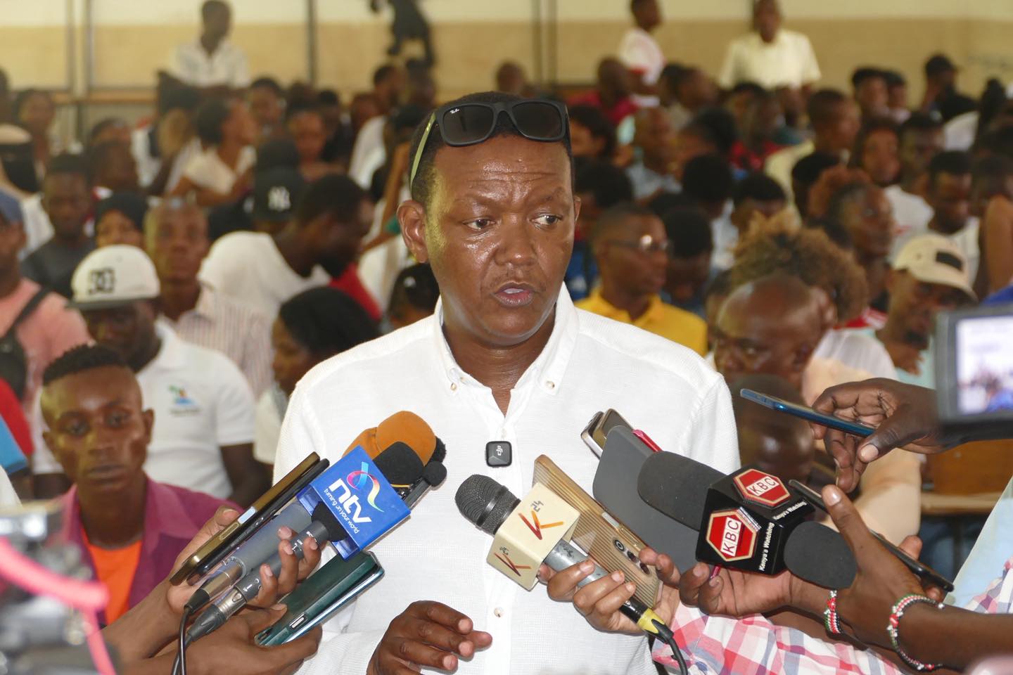 Dr Alfred Mutua, Labour Cabinet Secretary, speaking to journalists while surrounded by microphones during a recruitment drive in Mombasa on Wednesday