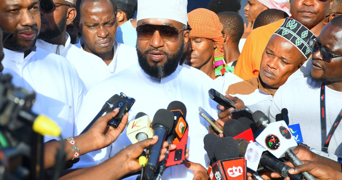 CS Hassan Joho speaks to journalists surrounded by microphones at Eid-ul-Adha prayers in Mombasa