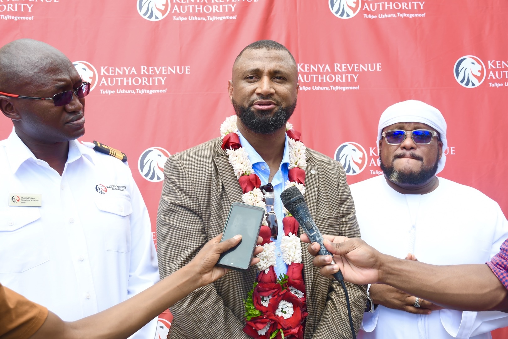 KRA crackdown smugglers Kenya — Commissioner Mohamed M'maka speaks to press at Sheikh Khalifa School Mombasa wearing flower garland